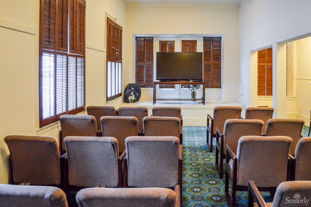 A small conference room with rows of chairs facing a large television.