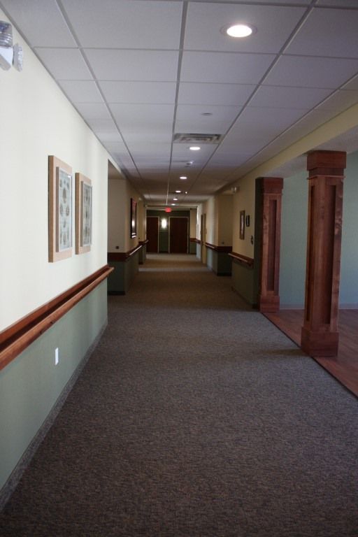 A long, empty hallway with decorative wooden columns and framed art on the walls.