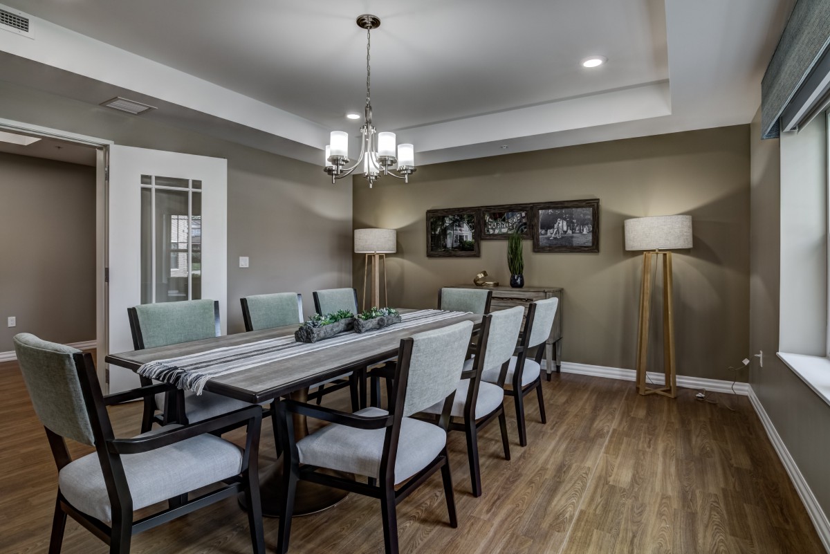 A modern dining room with a long table, chairs, and elegant lighting.