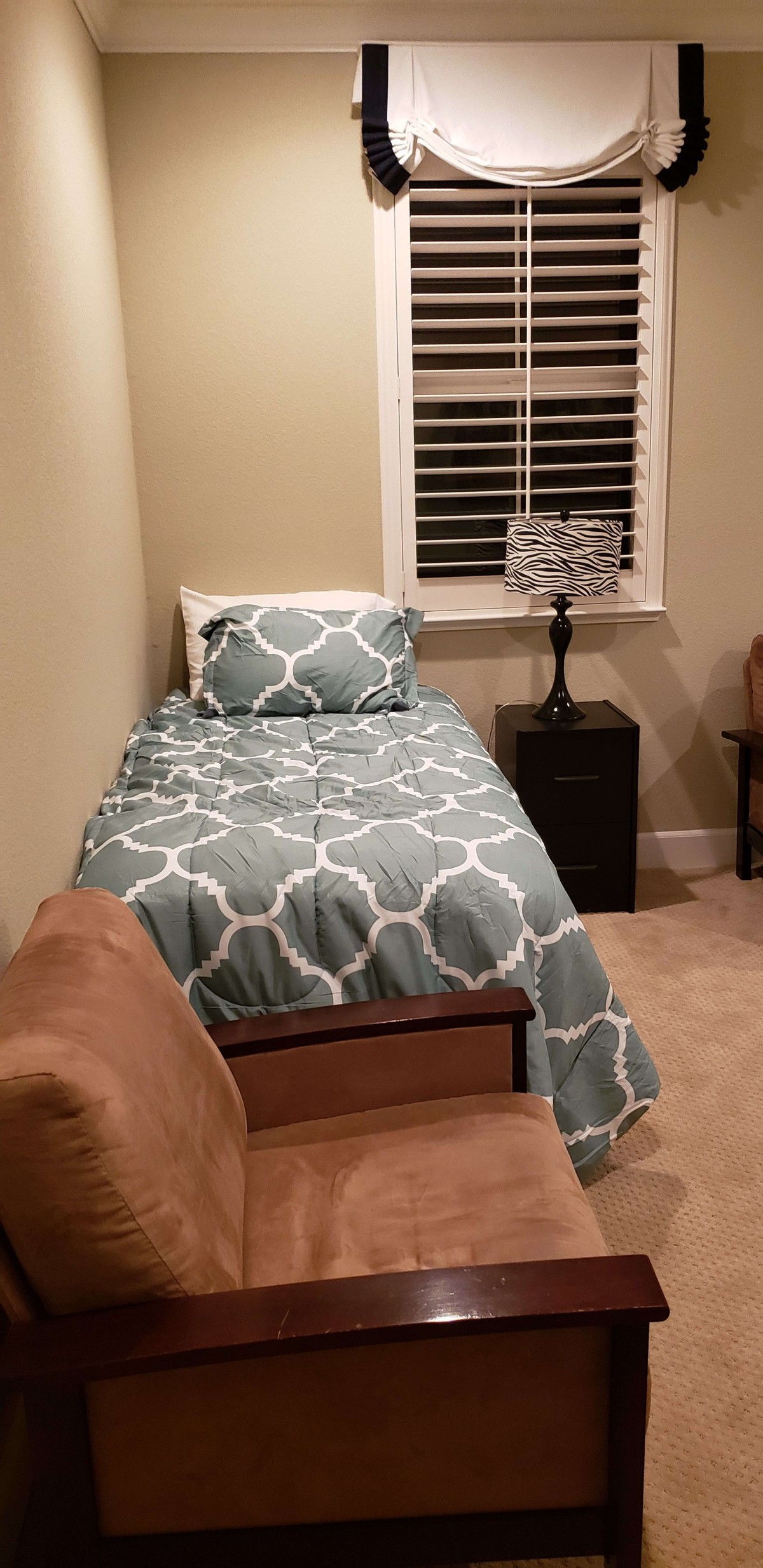 A cozy bedroom with a single bed, nightstand, and lamp.