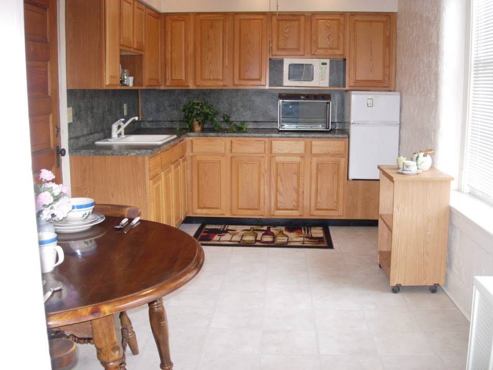 A cozy kitchen with wooden cabinets, a microwave, refrigerator, and a dining table.