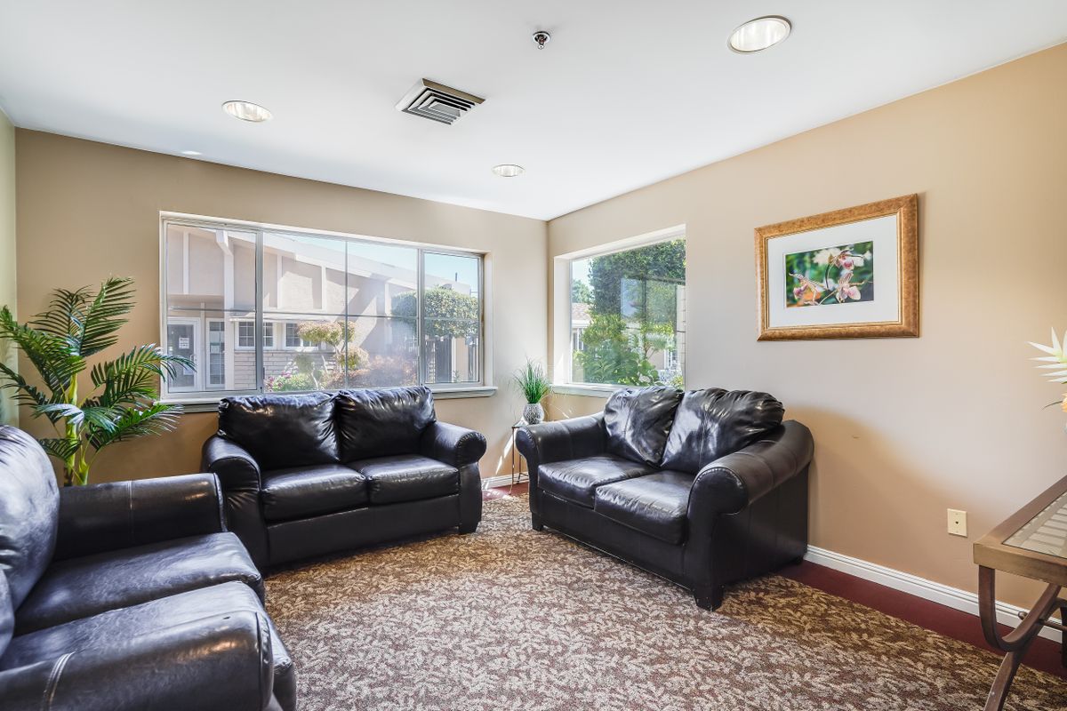 A cozy living room with black leather sofas and large windows.