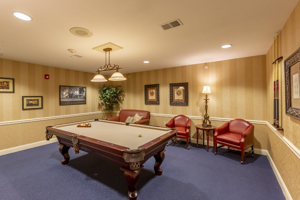 A cozy billiard room featuring a pool table, elegant lighting, and comfortable seating.