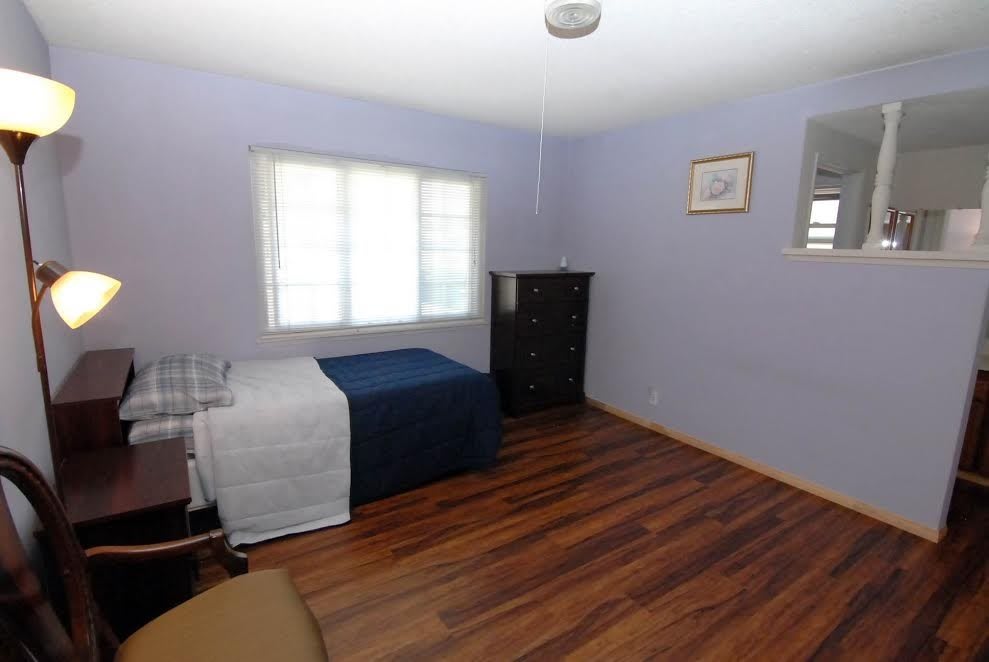 A minimalist bedroom with a single bed, dresser, and hardwood flooring.