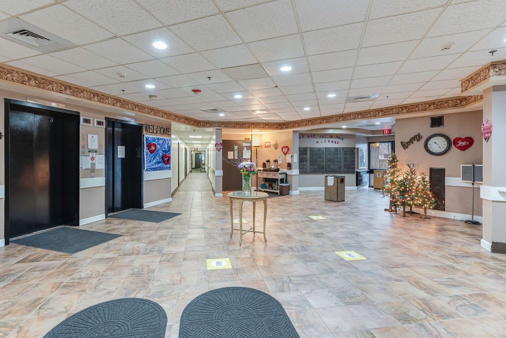 A spacious lobby with tiled flooring, a reception desk, and decorative elements along the walls.