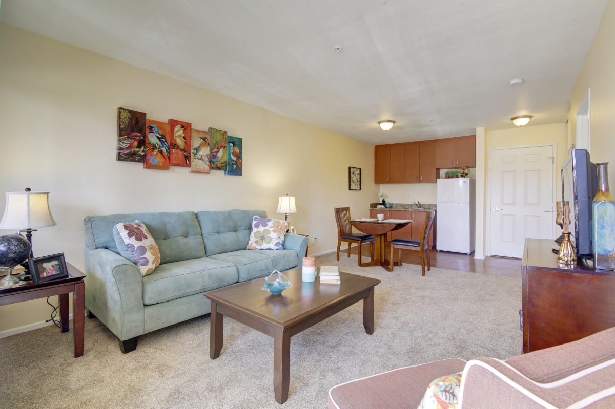 A cozy living room with a sofa and coffee table, adjacent to a small dining area and kitchenette.