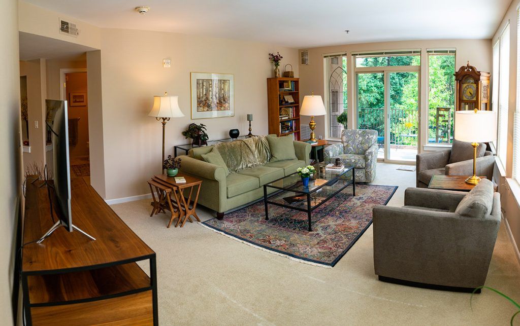 A cozy living room with a green sofa, coffee table, and bright natural lighting.