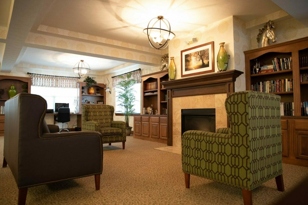 A cozy living room featuring comfortable armchairs, a fireplace, and elegant bookshelves.