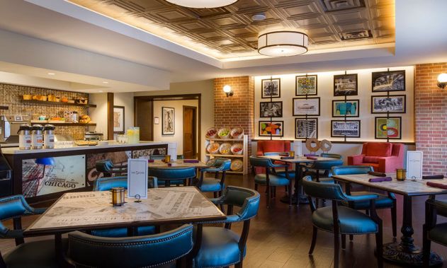 A cozy restaurant interior with blue chairs, wooden tables, and decorative artwork on the walls.