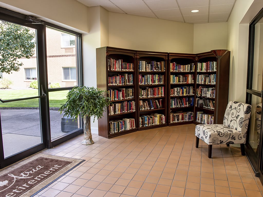 A cozy library corner with bookshelves and an armchair by the window.