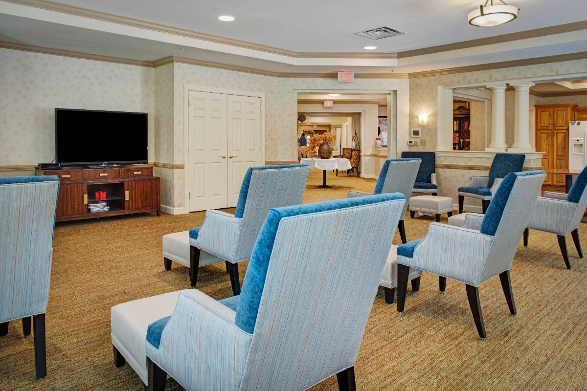 A comfortable seating area with blue cushioned chairs facing a television in a spacious room.