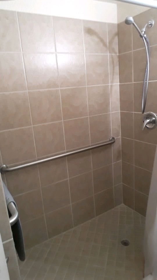 A tiled shower with a grab bar installed on the wall.