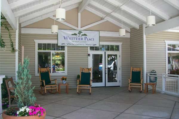 Front entrance with rocking chairs and a sign for Wheel Inn RV Park.