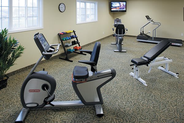 A small indoor fitness center with exercise bikes, a treadmill, and a rack of dumbbells.