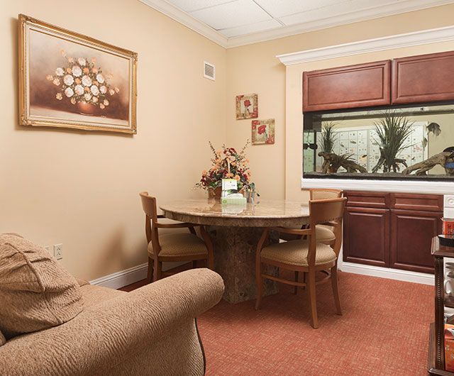 A cozy dining area featuring a round table with chairs, a sofa, and an aquarium built into the wall.