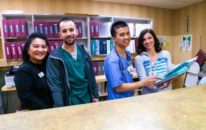 A group of healthcare professionals smiling at a hospital reception desk.