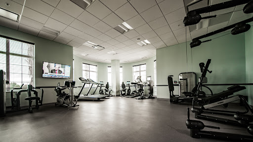 A modern gym setup featuring various exercise equipment and ample natural light.