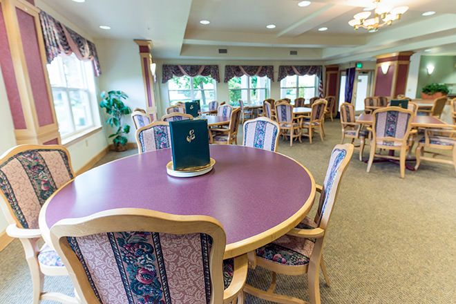 An elegantly decorated dining area with multiple tables and chairs, featuring large windows that allow natural light to fill the room.