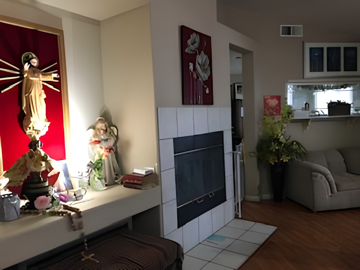 A cozy living room featuring a fireplace, decorative statues, and indoor plants.