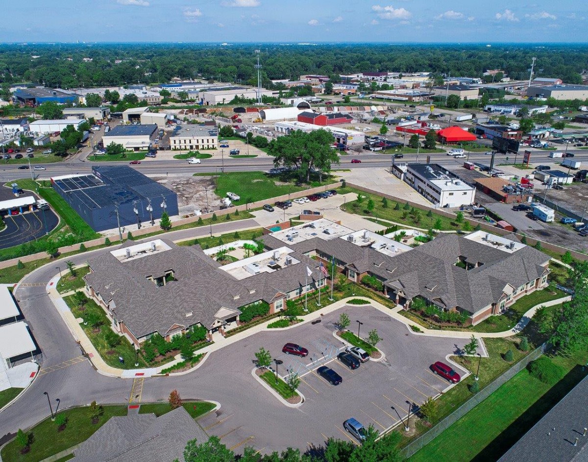 Aerial view of a suburban area with various buildings, parking lots, and surrounding roads.