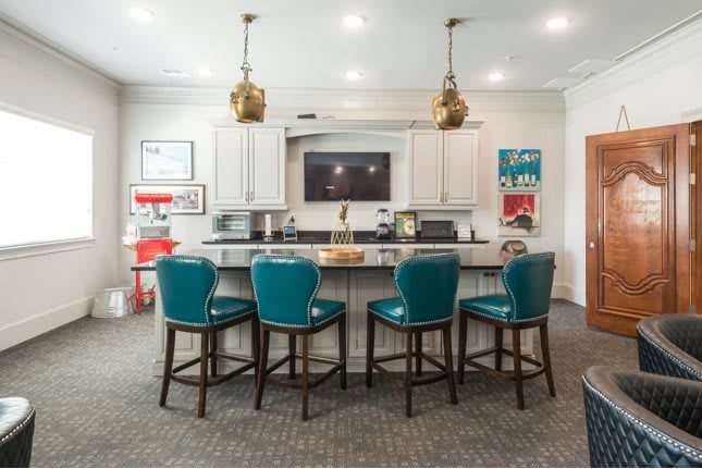 A modern kitchen with an island and teal bar stools, featuring stylish lighting and contemporary decor.