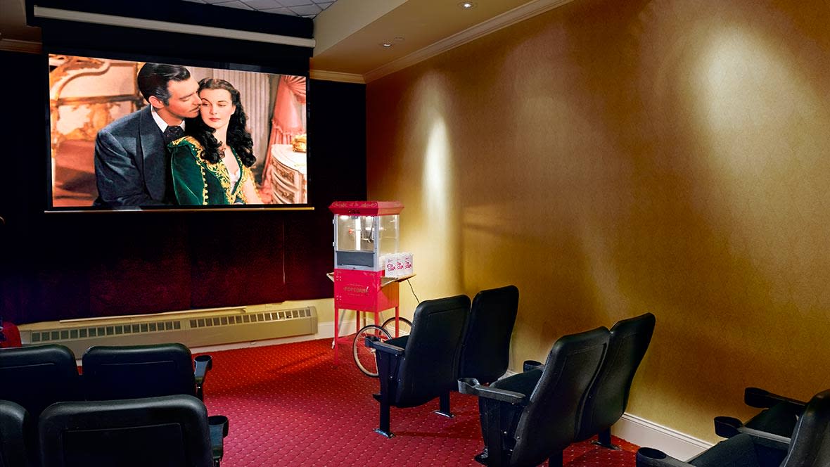 A cozy home theater setup with a classic movie on screen and a popcorn machine nearby.