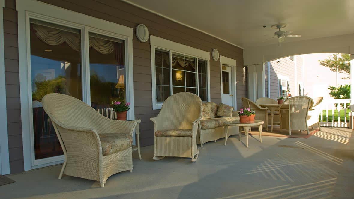 A cozy porch with wicker furniture set, including chairs and a sofa, perfect for relaxing outdoors.