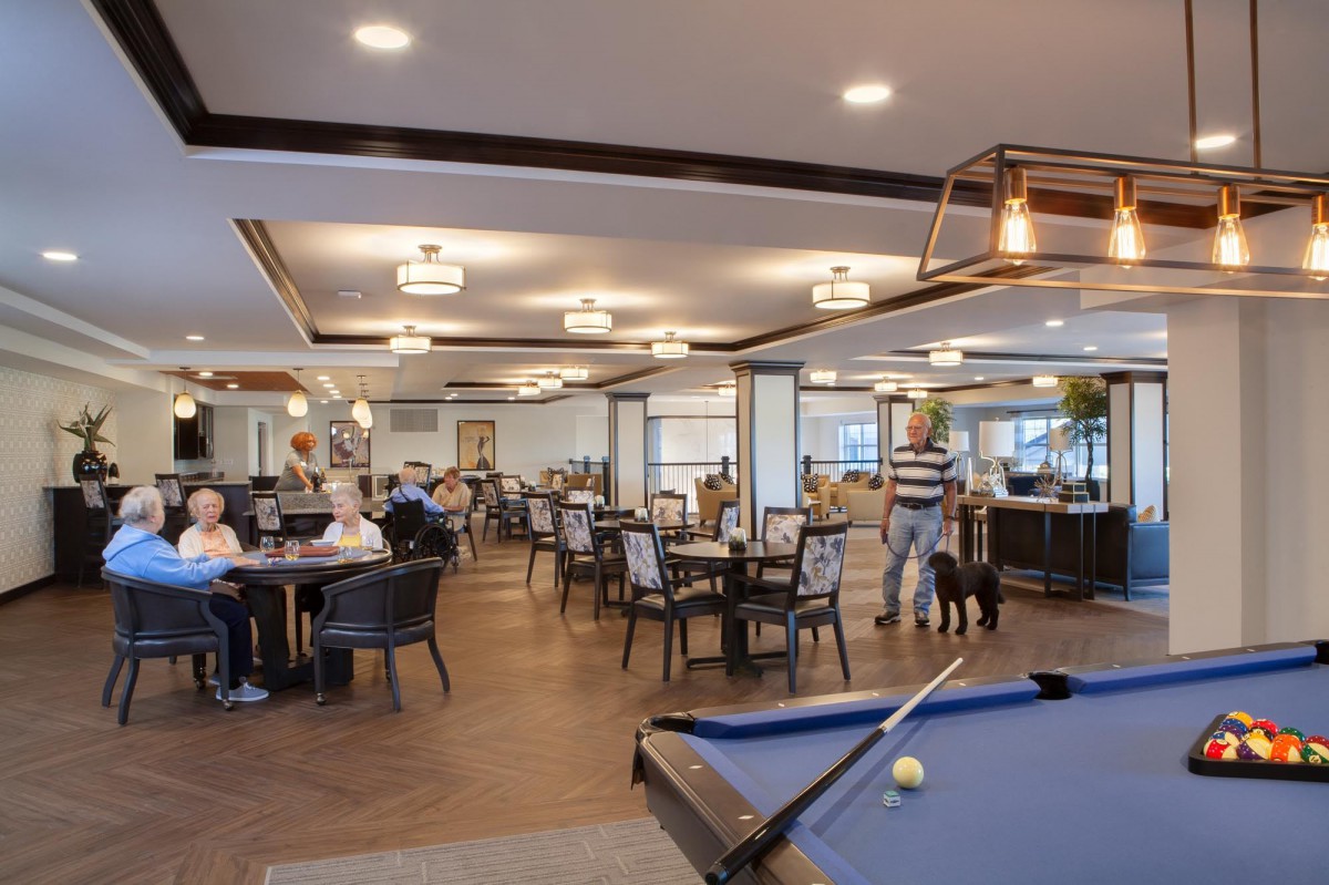 A spacious restaurant interior with a billiards table and people dining at various tables.