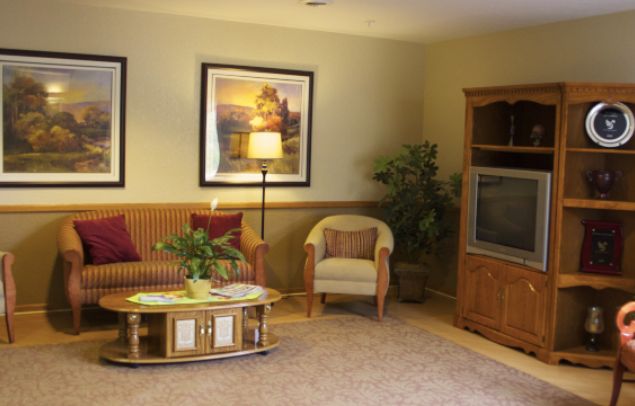 A cozy living room with a sofa, armchair, coffee table, and TV stand.