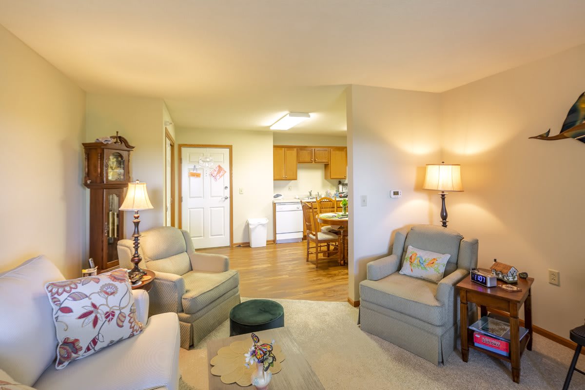 A cozy living room with comfortable armchairs and a view into the kitchen.