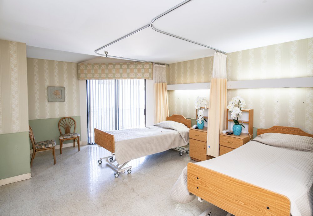 A well-lit hospital room featuring two patient beds separated by curtains.