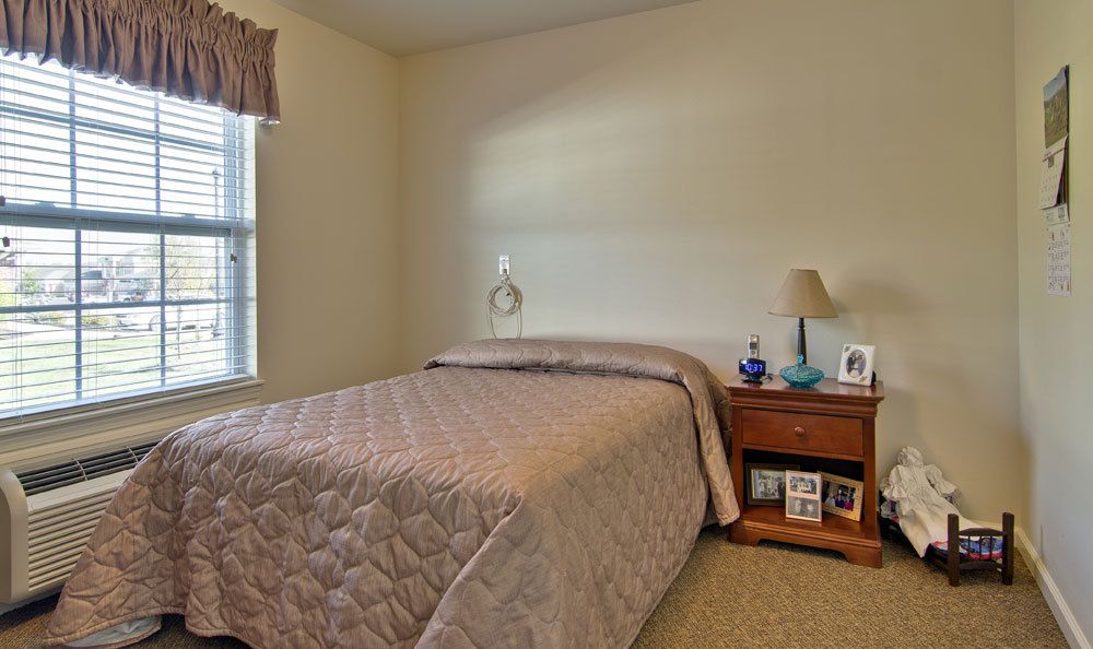 A cozy bedroom with a neatly made bed and a nightstand beside it.