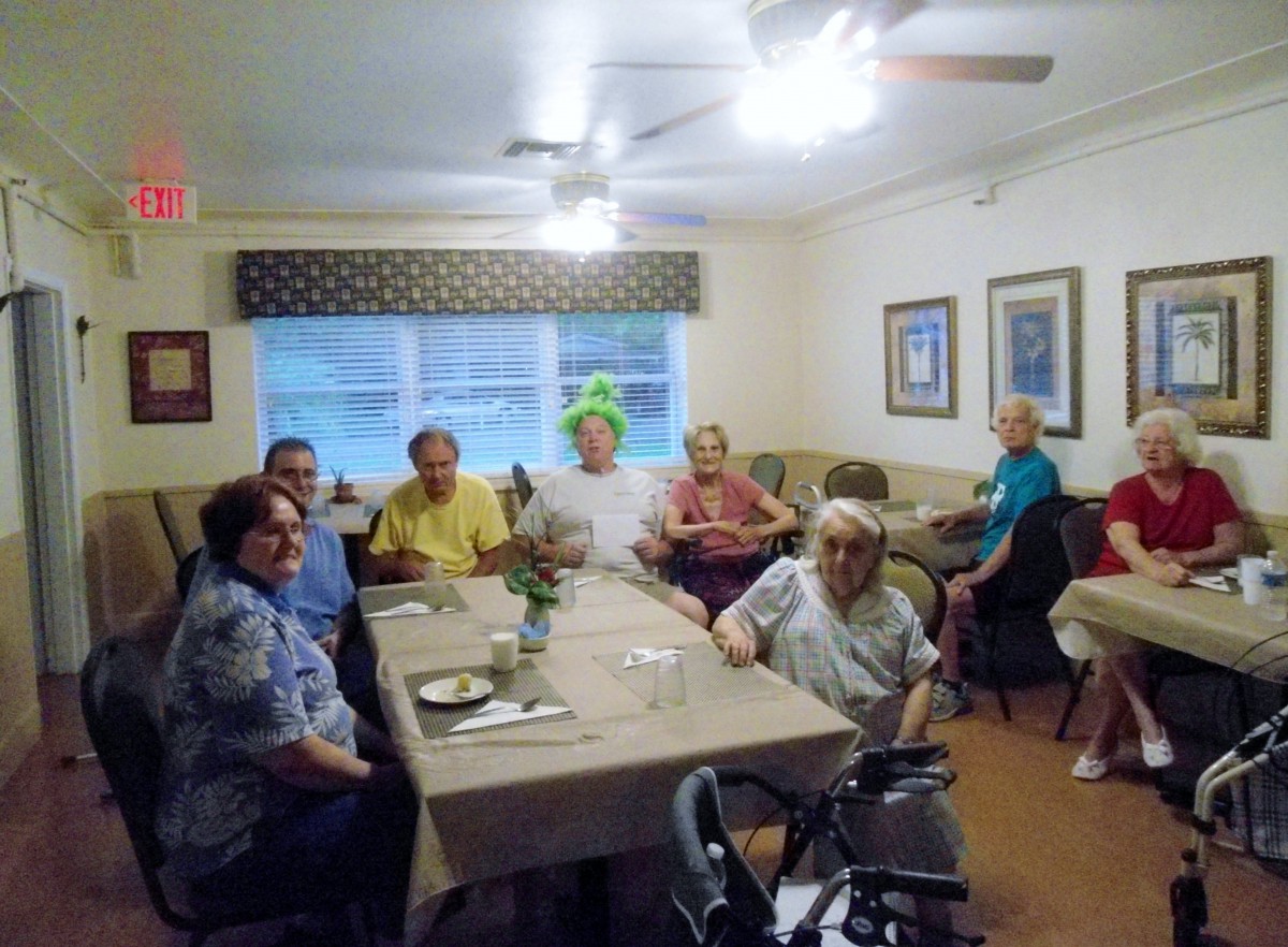 A group of elderly people gathering and socializing in a dining room.