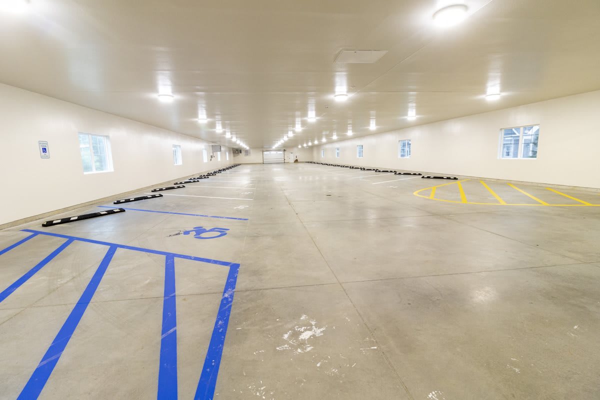 An empty indoor parking garage with marked handicap spaces on a concrete floor.