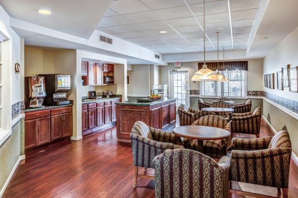 A cozy dining area with a kitchen, featuring wooden floors and comfortable seating.