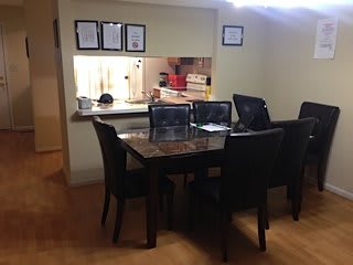 A dining area with a polished table and chairs, adjacent to an open kitchen.