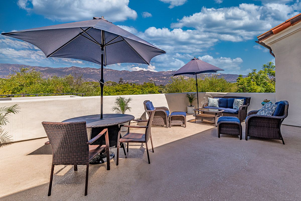 A spacious outdoor patio with comfortable seating and umbrellas, set against a scenic backdrop.