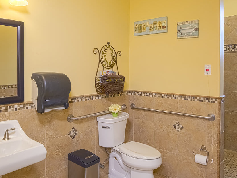 A well-organized bathroom with yellow walls, featuring a toilet, sink, and wall decorations.