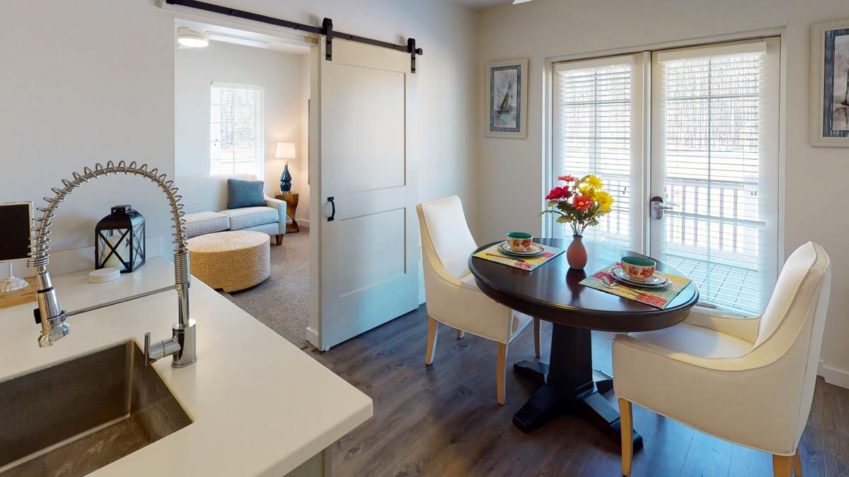 A cozy, modern interior featuring a dining area with a round table set for two, connected to a living room by a sliding barn door.