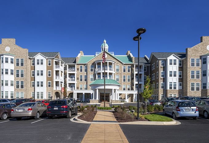 A modern residential apartment building with a well-maintained parking area and landscaping.
