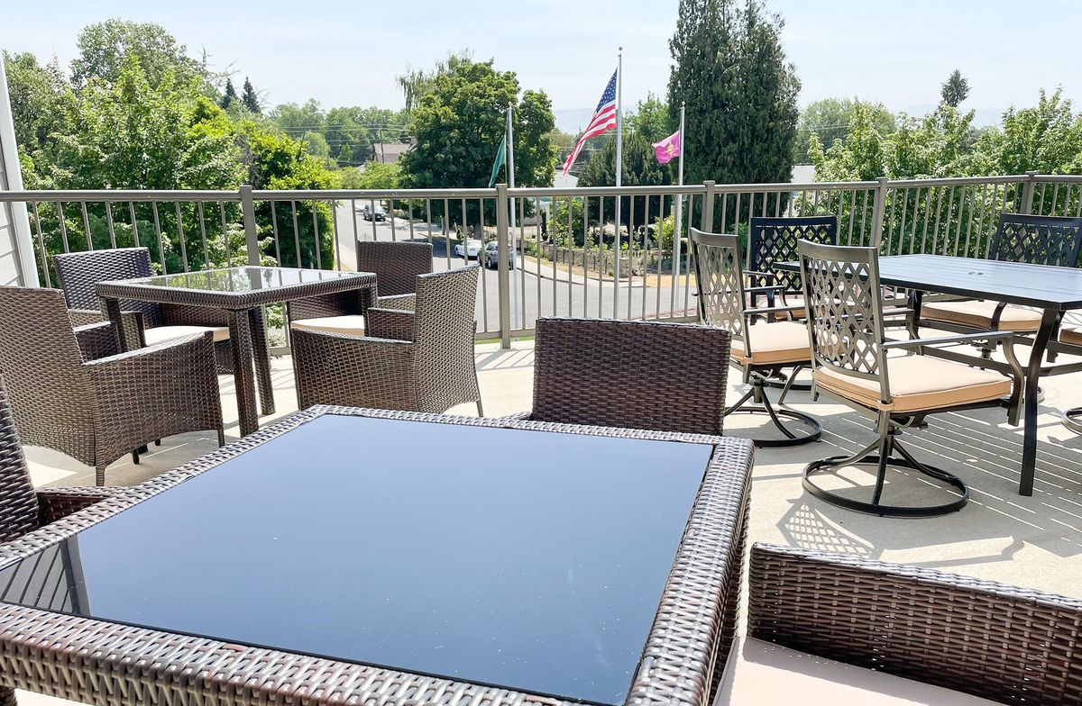 A sunny outdoor patio with modern furniture and a view of flags in the distance.