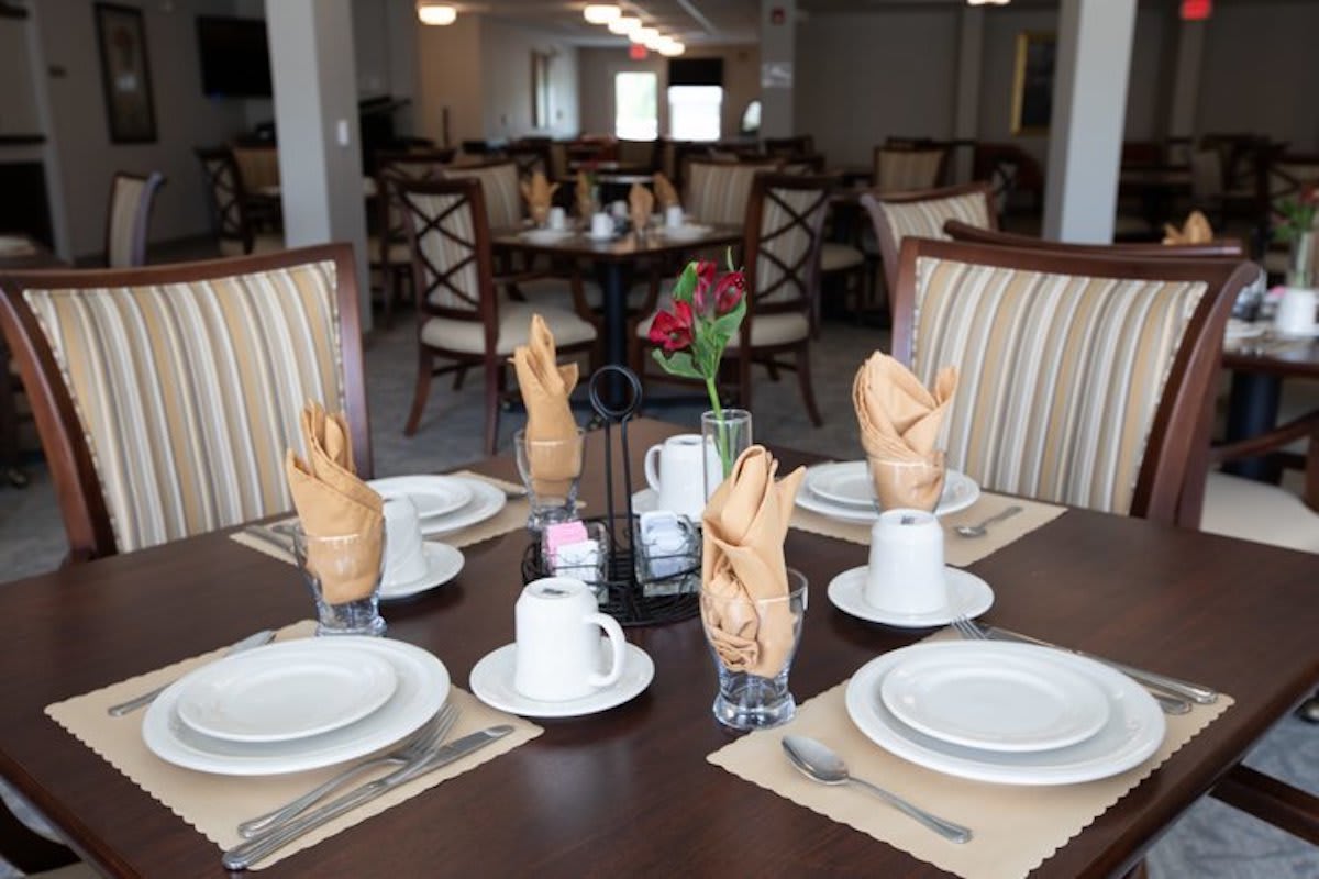 An elegantly set dining table in a restaurant with plates, cups, and neatly folded napkins.