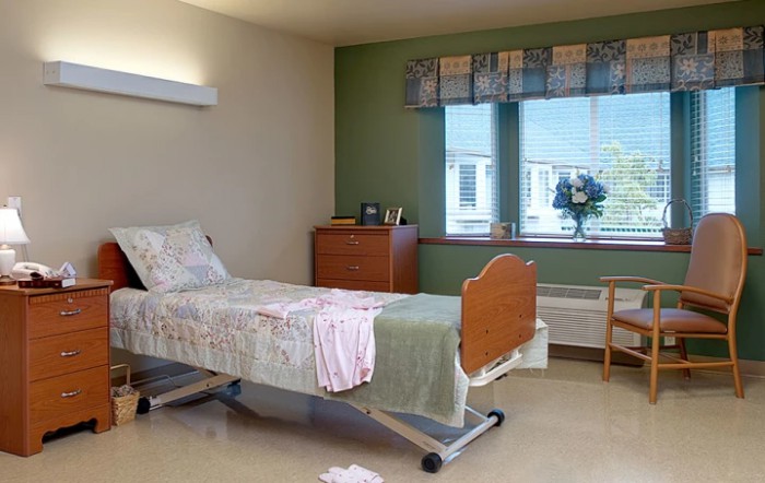 A hospital room with a single bed, a window, and basic furnishings.