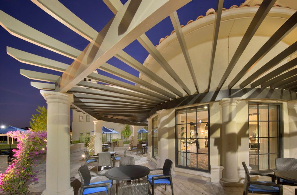 A modern outdoor seating area with a pergola and patio furniture, captured in the evening.