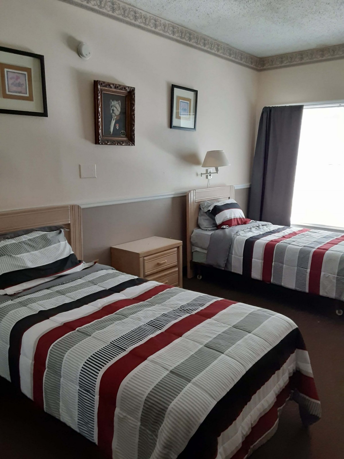 A neatly arranged bedroom with twin beds featuring striped bedding and wall decor.