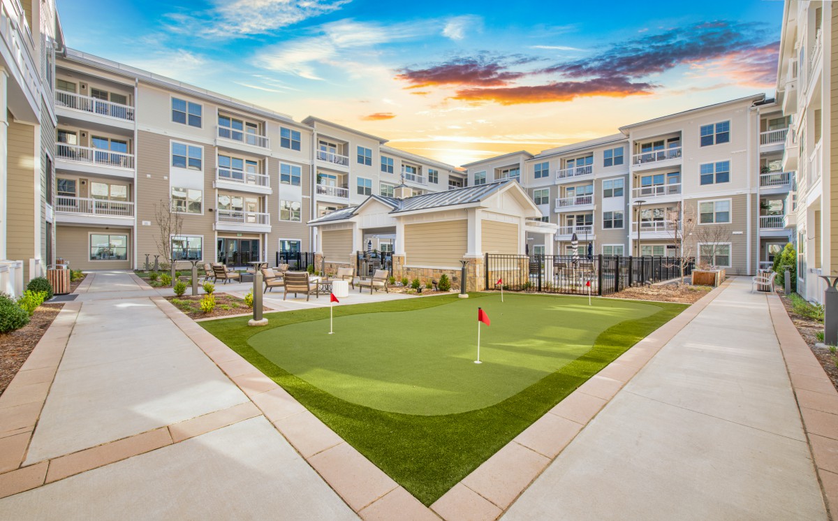 A modern apartment complex featuring a landscaped courtyard with a putting green.