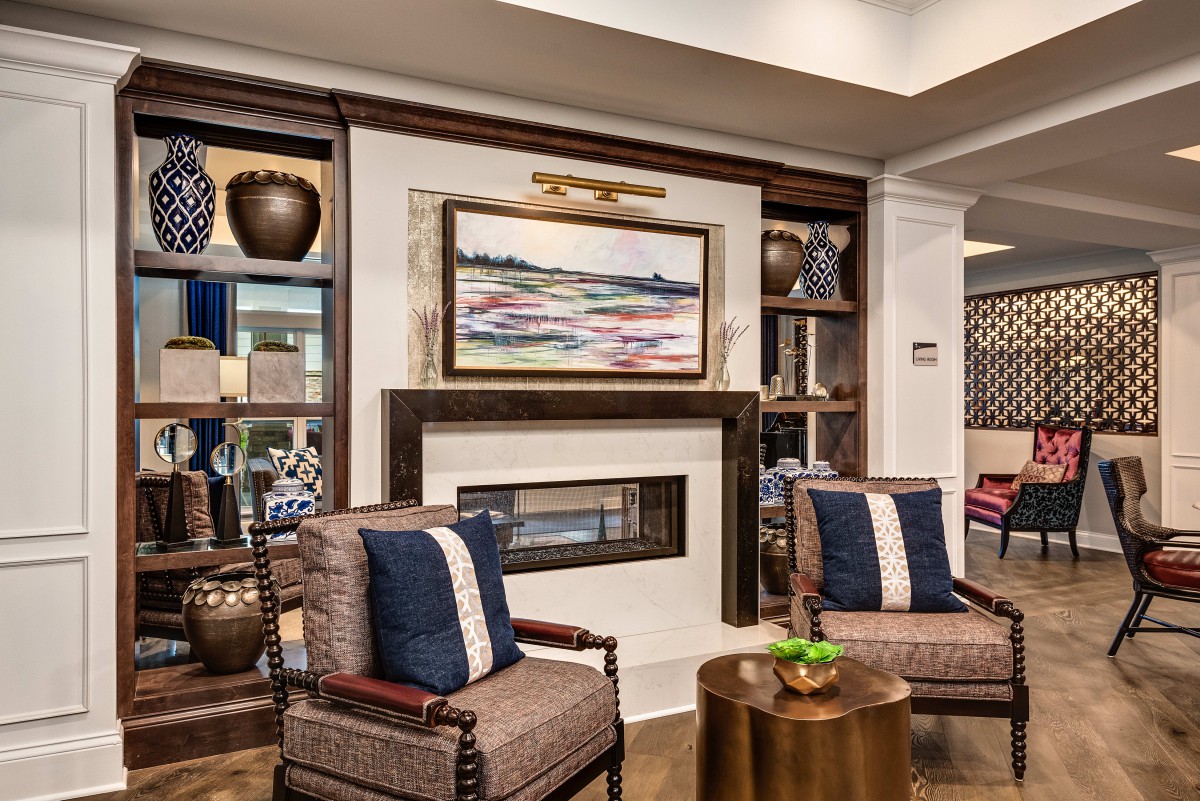 A beautifully designed living room featuring a central fireplace adorned with modern artwork, flanked by stylish chairs and bookshelves.