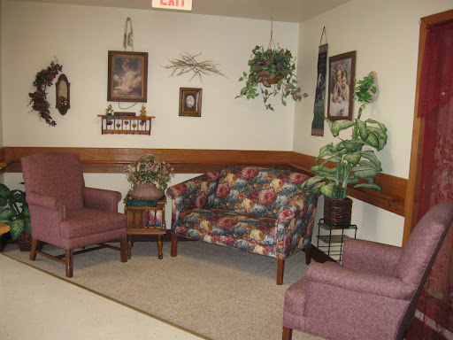A cozy waiting area featuring floral patterned seating and decorative plants.