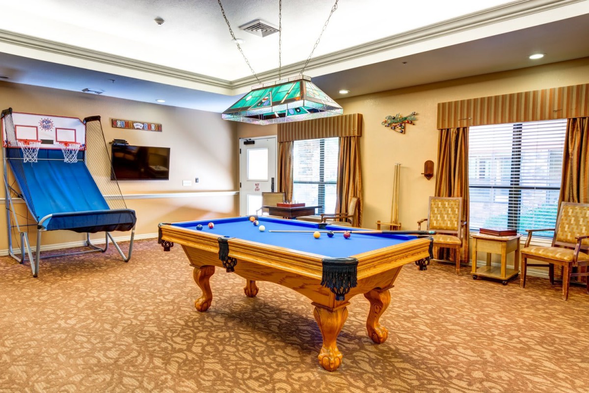 A well-lit game room featuring a blue felt pool table and various recreational amenities.