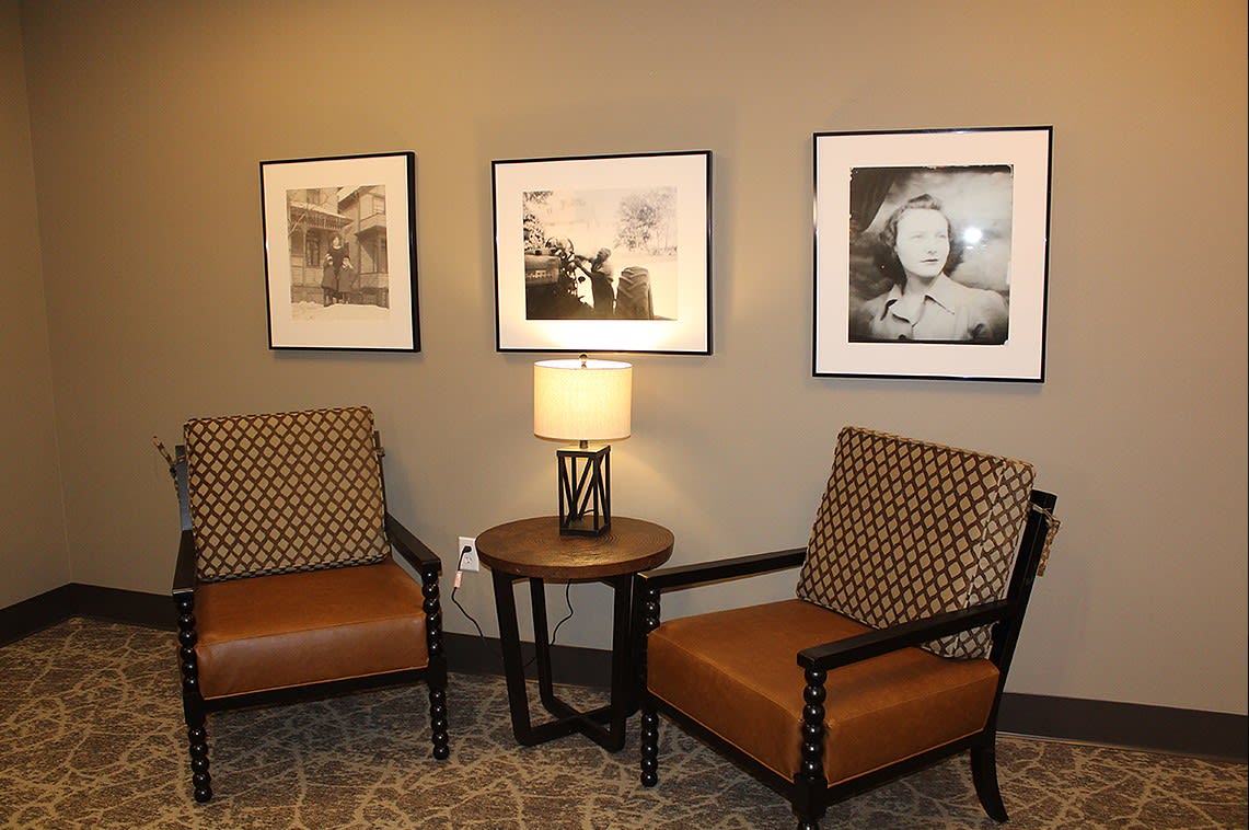 A cozy corner with two armchairs, a small round table, and framed pictures on the wall.